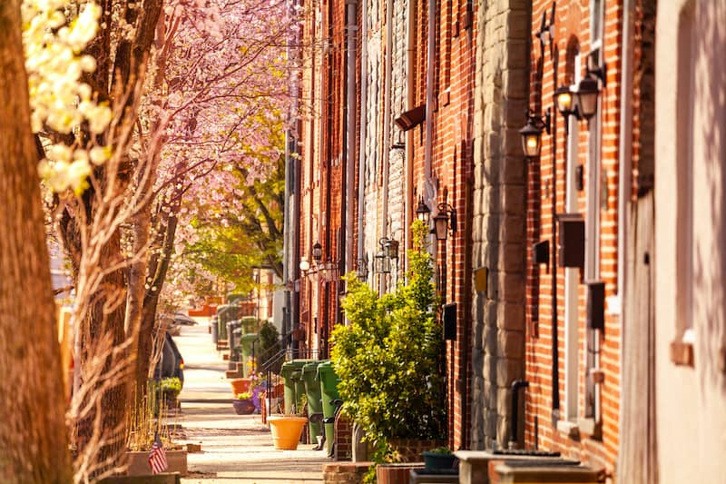 RHB Assets From IGX: A street view of brick houses with cherry blossom trees in Baltimore, Maryland.