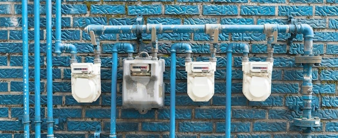 Home utilities against blue brick wall.