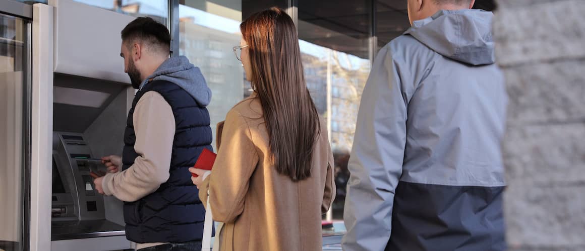 People standing in line at an ATM.