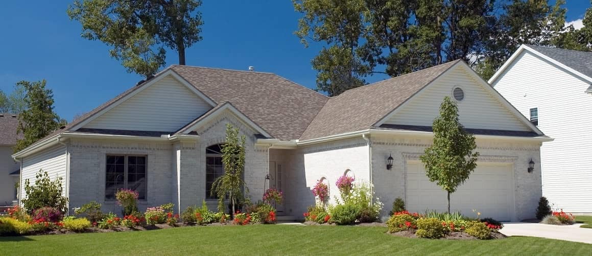 A white house nestled among trees in a suburban area.