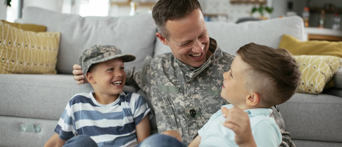 Military father smiling with his two young sons.