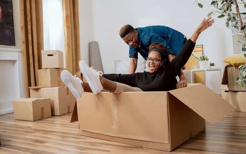 Person pushing another person around in a moving box and they're both laughing.