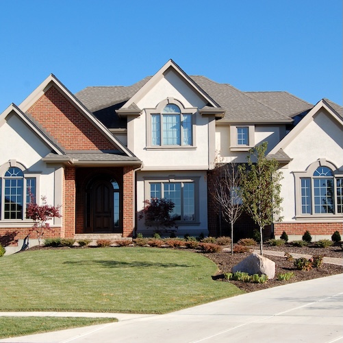 Large home with brick accents and landscaped front lawn.