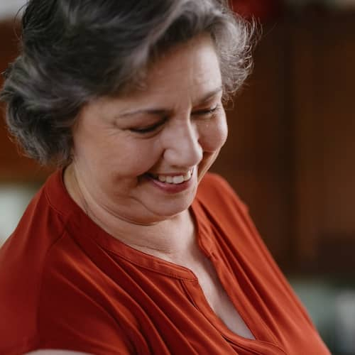 Woman doing dishes in her kitchen, smiling.