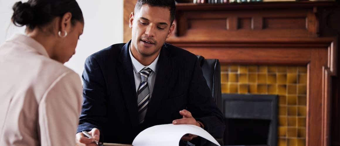 Woman meeting with a lawyer in his office and looking at papers together.