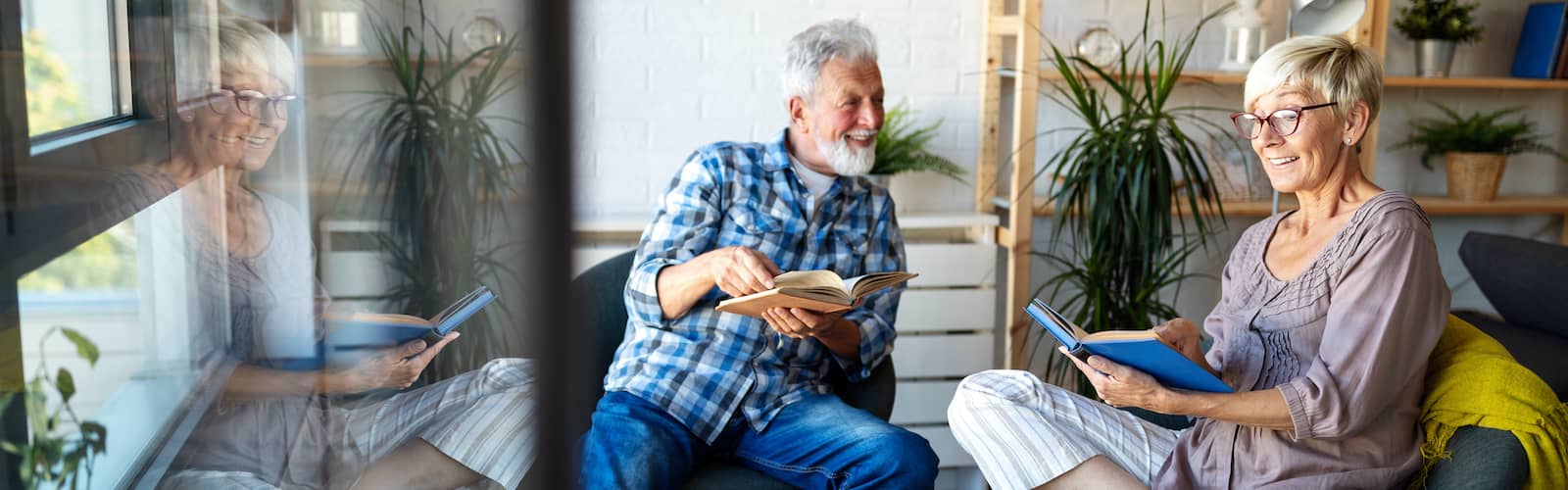 An elderly couple sitting and reading together having a good time.