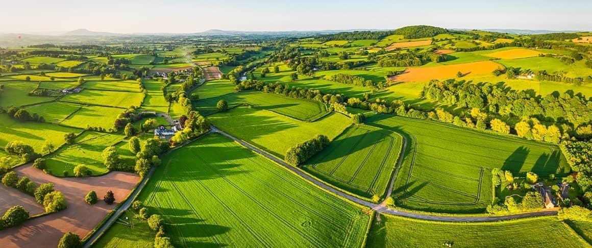 A breathtaking aerial view of lush green fields and gently rolling hills in the serene countryside.