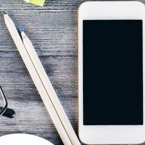 Mortgage calculator, pencils and phone on wooden table.