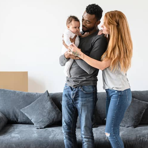 A couple with a baby in a new home, symbolizing the joy of starting a family in a new place.