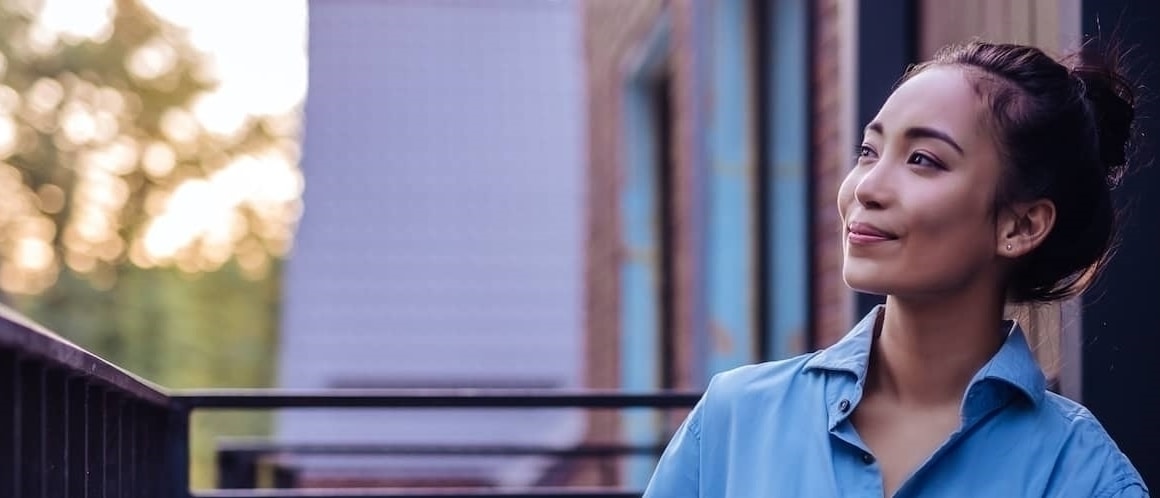 A woman in a blue shirt enjoying the view from her balcony.