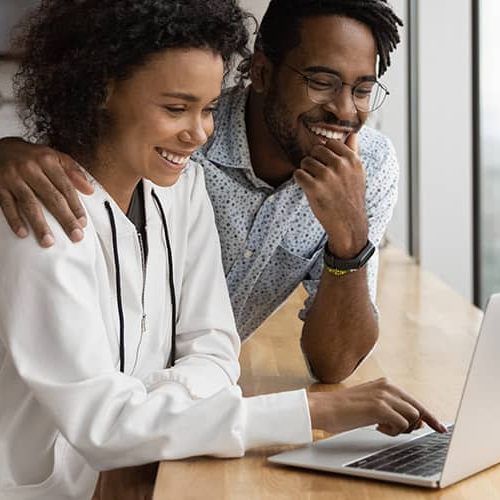 A couple viewing information together on a laptop.