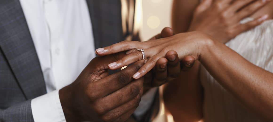 Person putting engagement ring on fiancée.