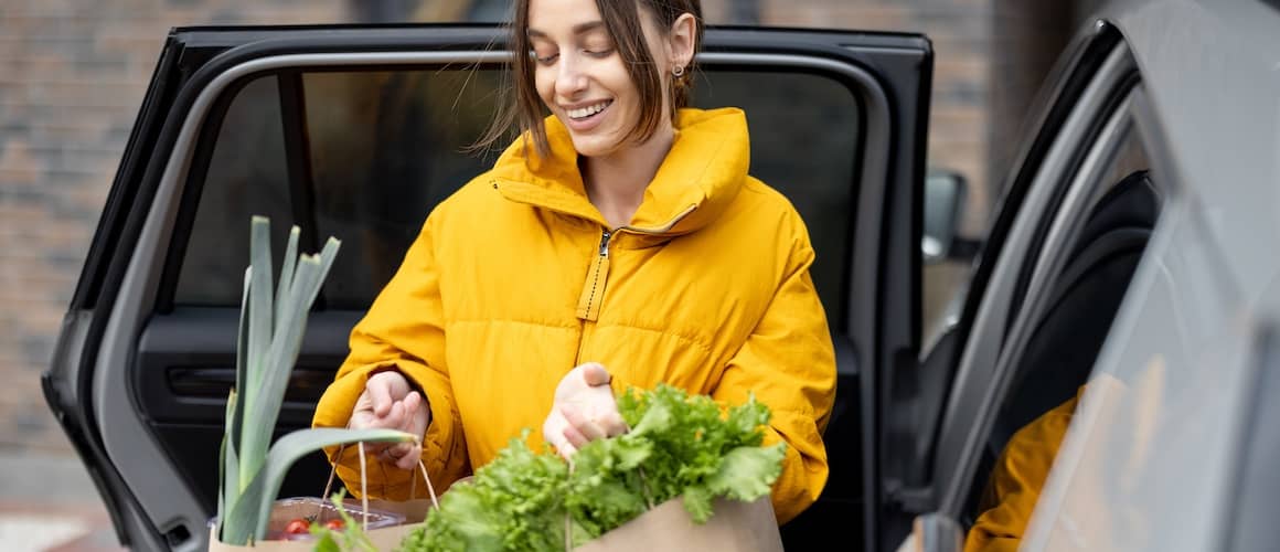 Women in yellow jacket getting groceries from her car