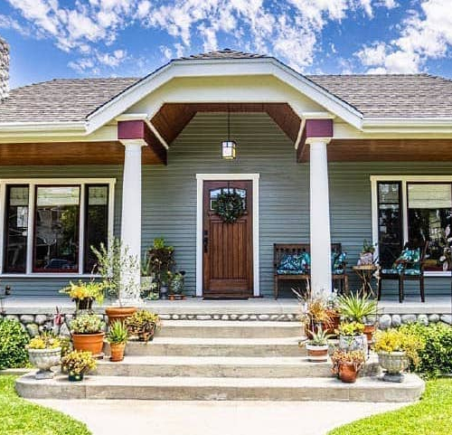 A cozy house with a charming porch and a well-maintained lawn.