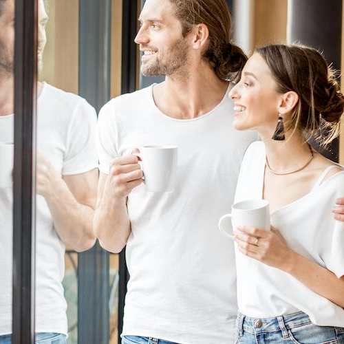 A couple looking at a window, potentially contemplating real estate views or assessing a property.