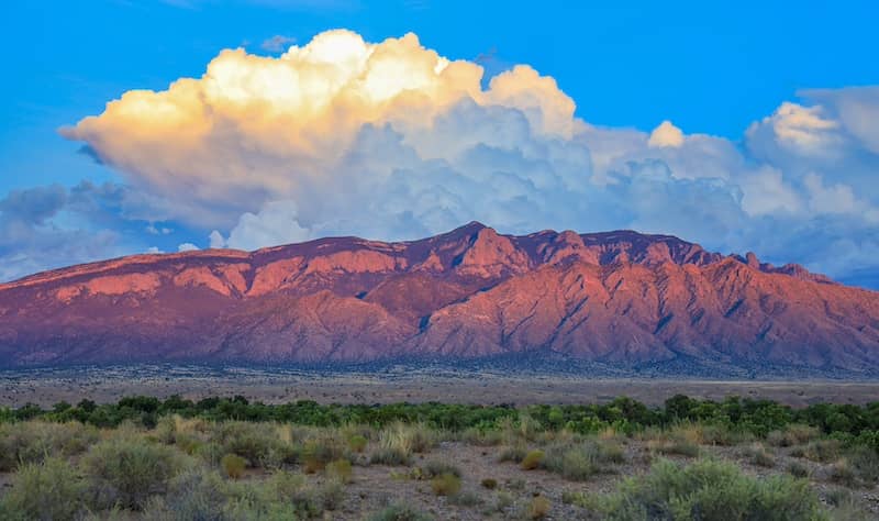 View of the Sandia mountains in New Mexico with large clouds behind.