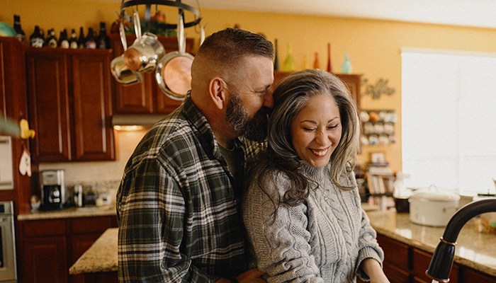 Husband holding wife while she washes the dishes.