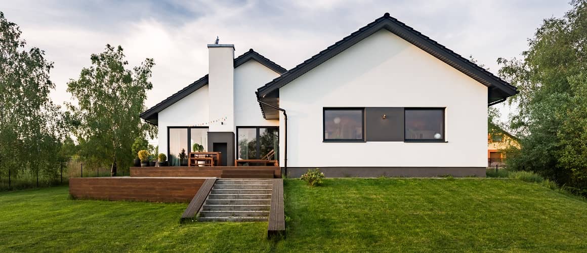 A white minimalistic house with a black roof, showcasing a simple yet stylish residential design.