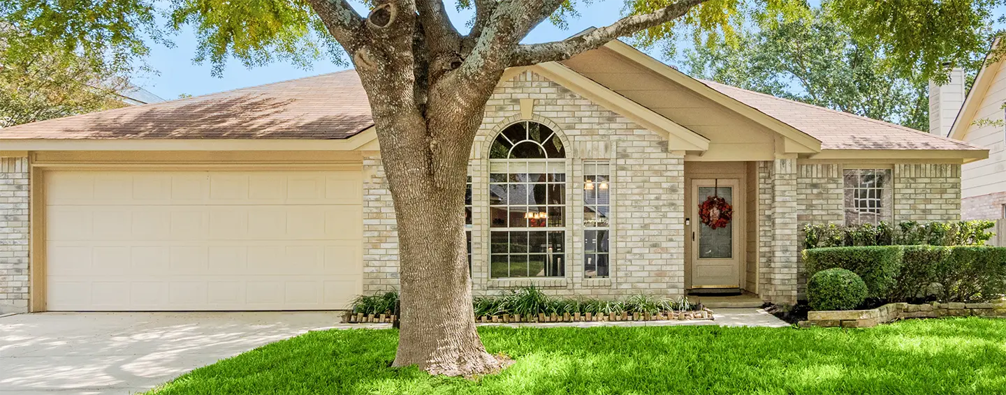 Front view of a traditional home with a big tree in the yard.