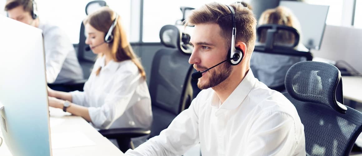 Man in customer service in an office working with a headset and a laptop.