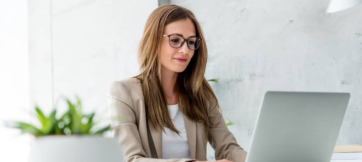 Businesswoman working on a laptop, indicating remote work or managing finances in a professional setting.