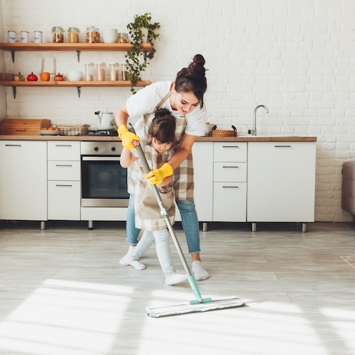 Mother mopping the floor with her daughter helping.