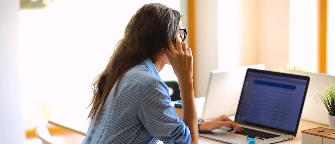 Young woman sitting at her desk and talking on. her cell phone.