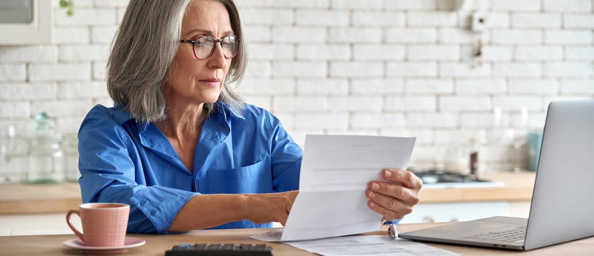 Older senior woman wearing glasses while working on her laptop at home.