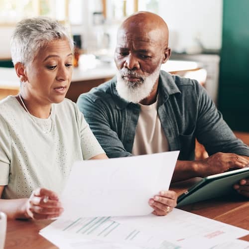Couple reviewing a document together at the kitchen table.
