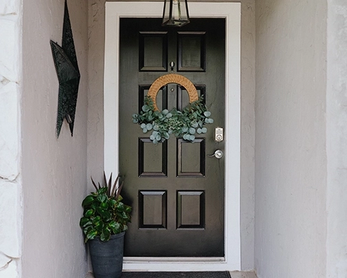 Grey house with stone features and black door.