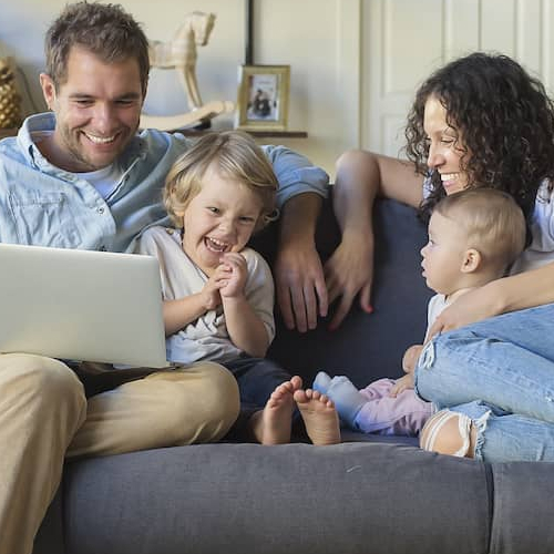 A family sitting comfortably on a couch, possibly in a home setting.