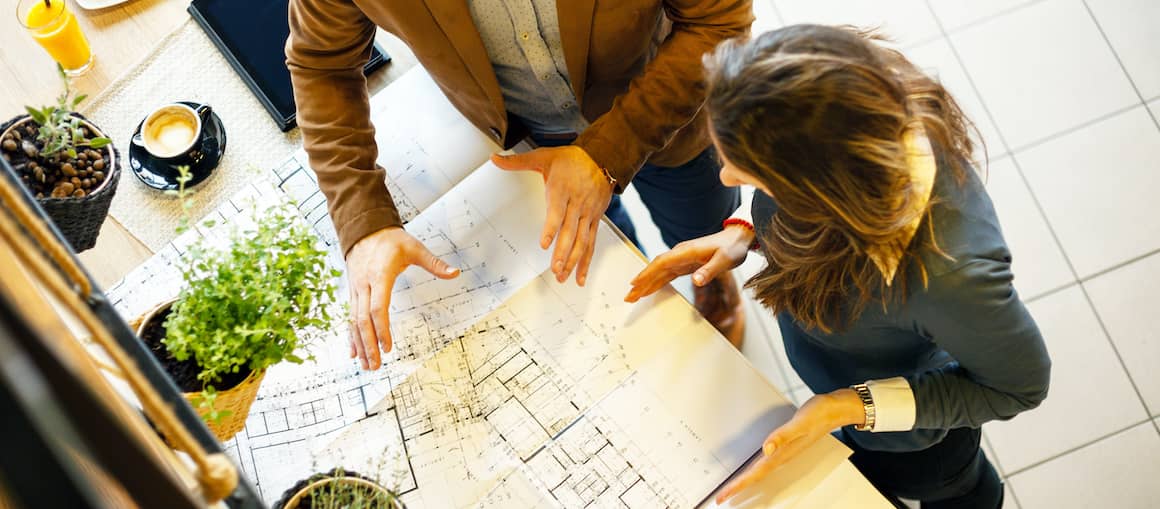 Architects in discussion, reviewing plans and blueprints in an office setting.