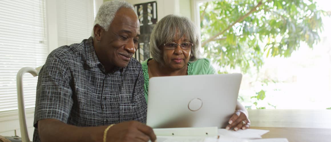 A couple planning and discussing their future while looking at a laptop.