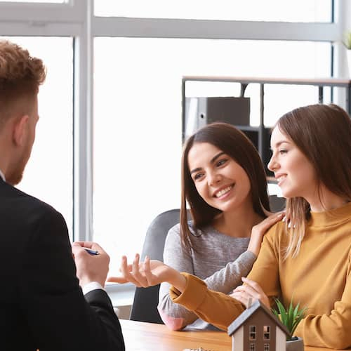 Same-sex female couple with a broker, potentially representing a diverse couple working with a real estate broker.
