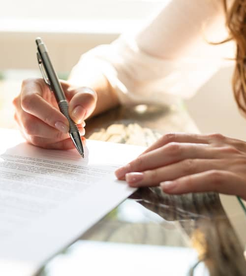 A woman signing a contract, suggesting engagement in a real estate agreement or mortgage-related documentation.