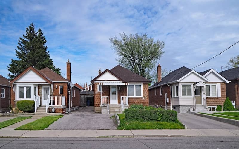 Row of brick and white sided bungalow homes on a sunny day.