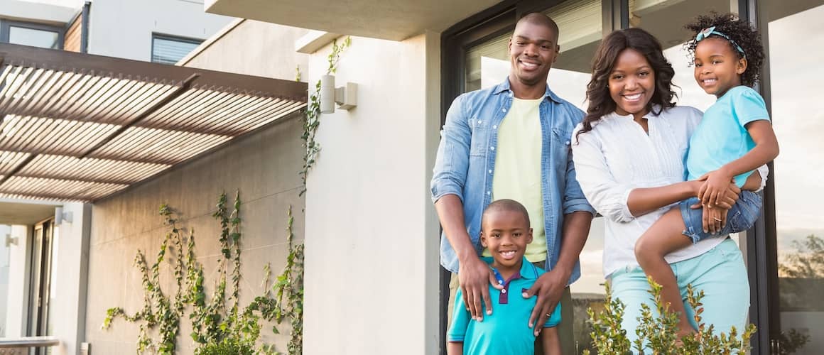 An African American family outside a modern home, portraying a sense of homeownership and family life.