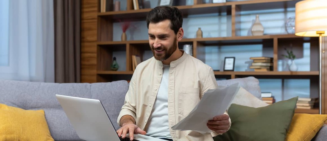 Man looking at paperwork on couch.