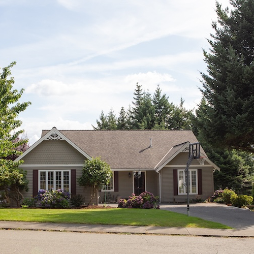 Ranch house with bay window and basketball hoop in driveway.