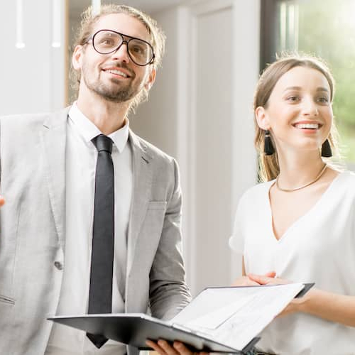 A real estate agent with a file showing and describing a house to a woman.