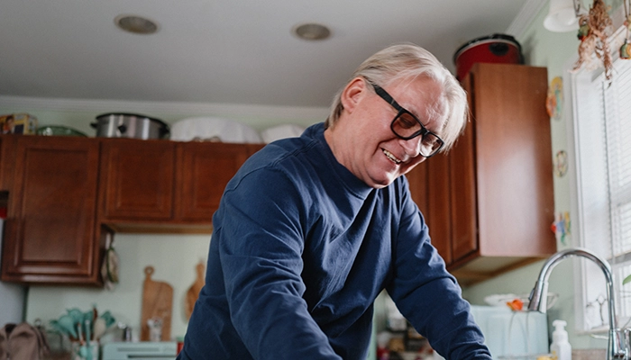 Man with glasses smiling while putting coffee cup in the dishwasher.