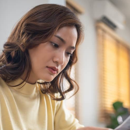 Woman reading documents while sitting in front of the computer.