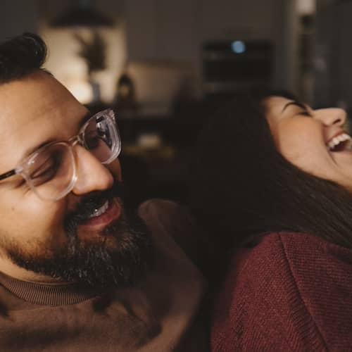 Couple snuggling and laughing together on couch.