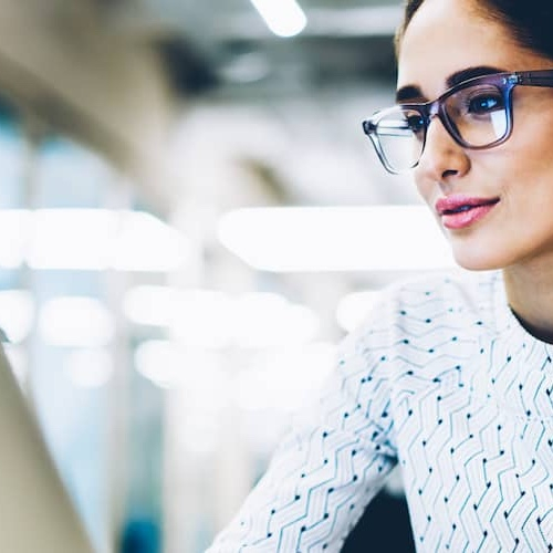Woman wearing glasses and working on laptop.