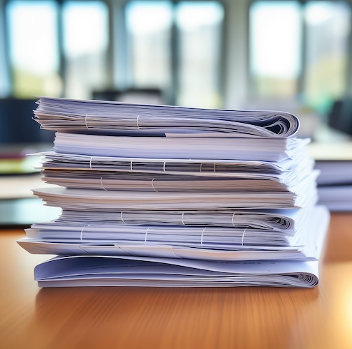 Large stack of paperwork on a desk.