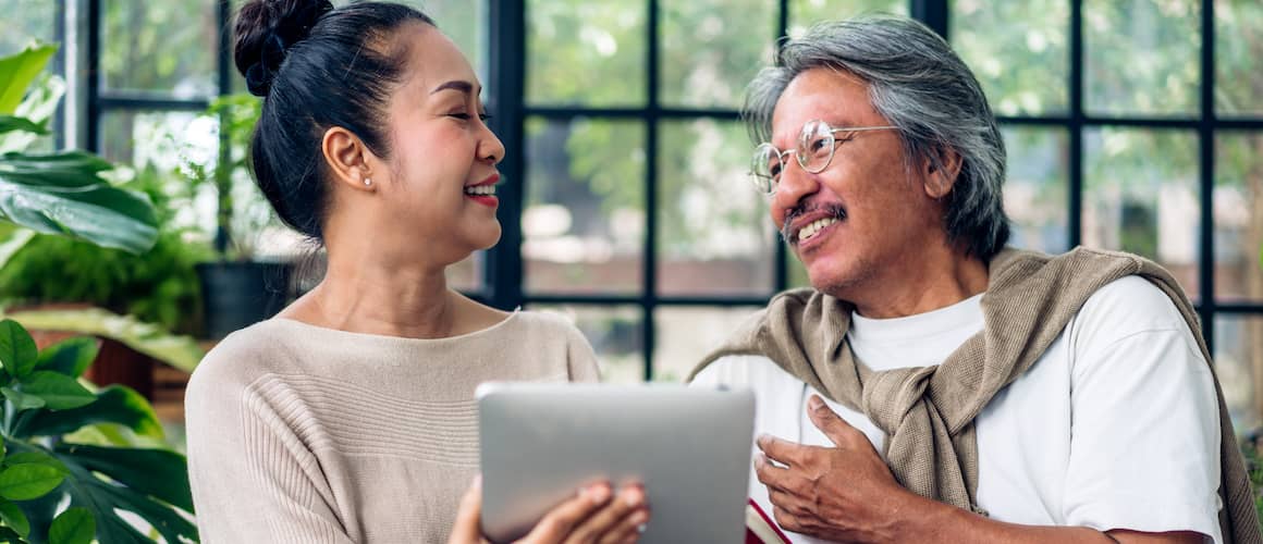 Older couple in all seasons room looking at tablet together and smiling.