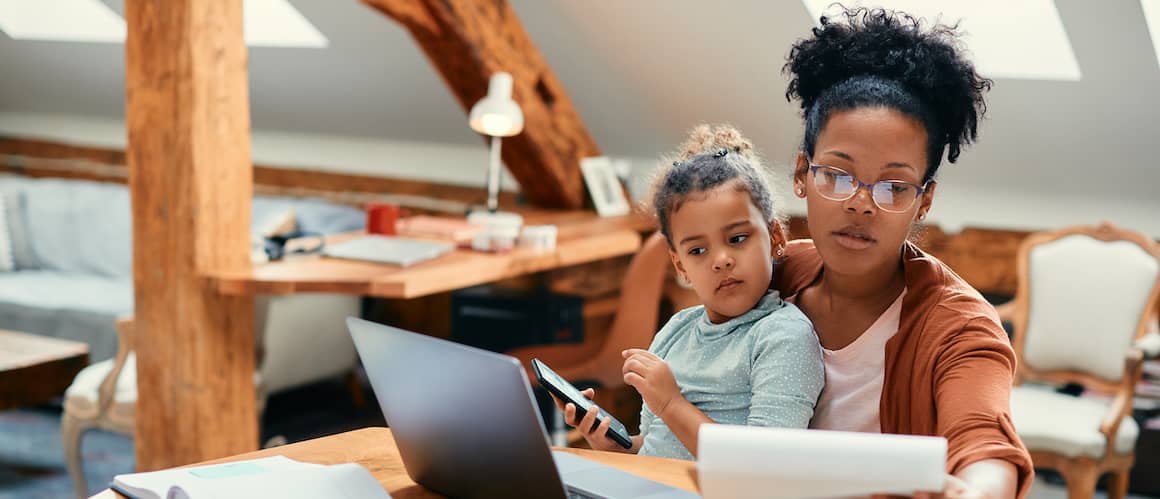 An African American mother working on finances with her daughter, likely depicting financial education or planning.