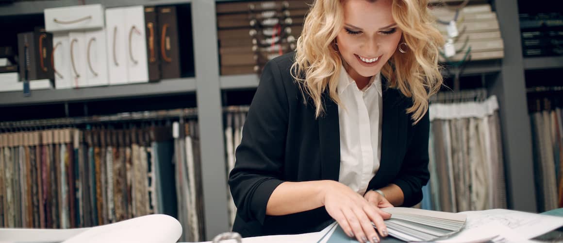 Blonde woman looking at paint swatches and smiling while planning renovations.