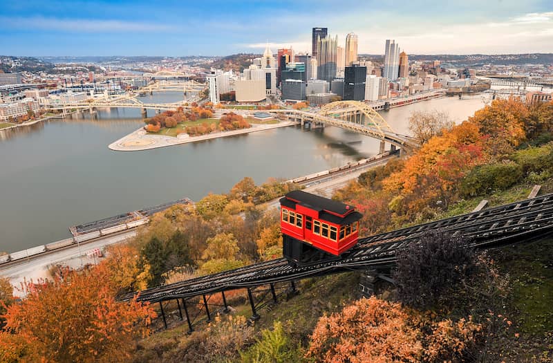 RHB Assets From IGX: Scenic view of the Pittsburgh skyline at sunset, with the city's iconic bridges and skyscrapers reflecting on the water.