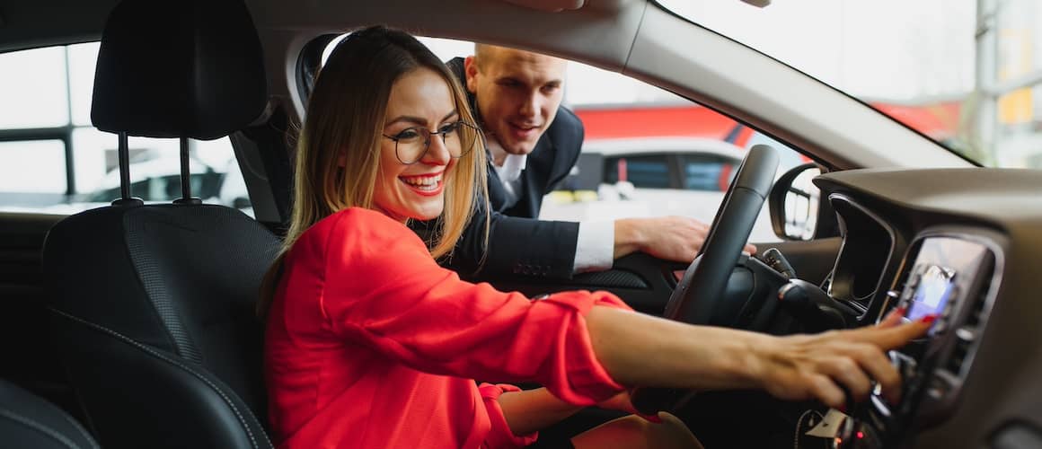 Woman talking to salesperson while testing out car.